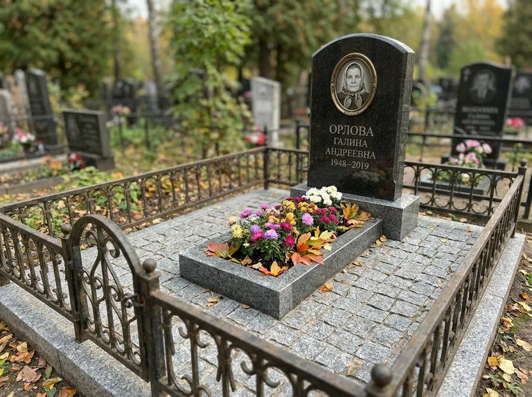 Благоустроенное захоронение с гранитной плиткой, оградой и цветником в Красноярске
