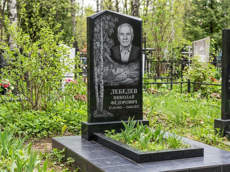 Памятник с гравировкой берёзы: вертикальная стела со скошенным верхом — берёза и стая птиц в небе, гранитный цоколь с тёмной плиткой, работа «Лебедев» в Красноярске