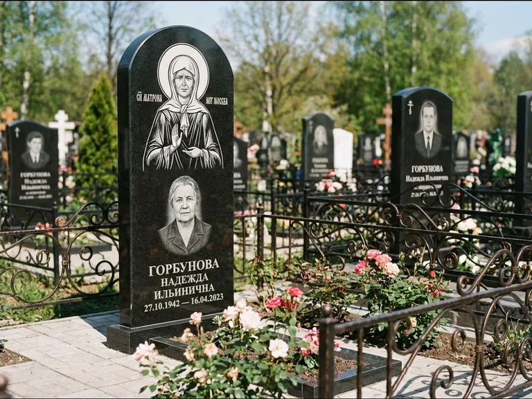 Памятник с гравировкой иконы: стела с арочным верхом и киотом под образ — гравировка образа Матроны Московской, гранитный цоколь с тёмной плиткой, работа «Ковалёв» в Красноярске