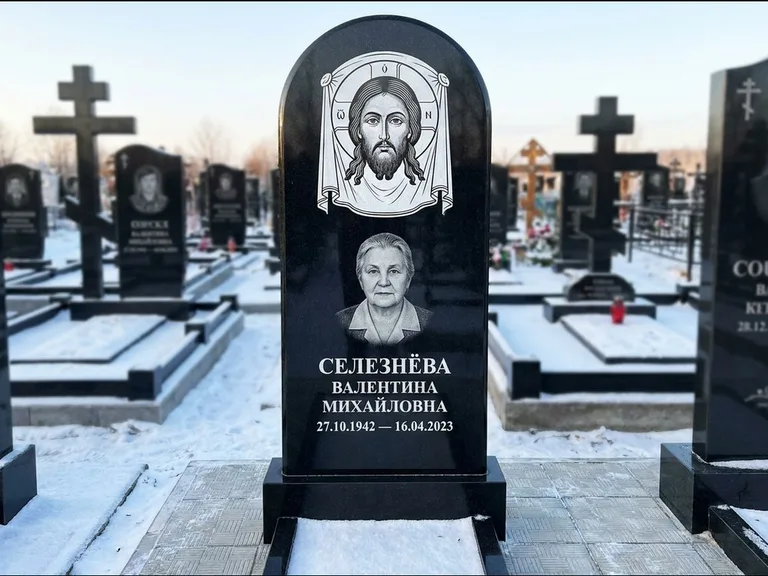 Памятник с гравировкой иконы: небольшая скромная одиночная стела с именной иконой — золочёный нимб на образе, аккуратный участок с газоном, работа «Ковалёв» в Красноярске