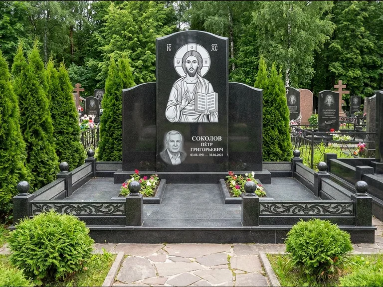 Памятник с гравировкой иконы: широкая горизонтальная лежачая плита-стела — икона в резной рамке-киоте, серая гравийная отсыпка с бордюром, работа «Богданова» в Красноярске