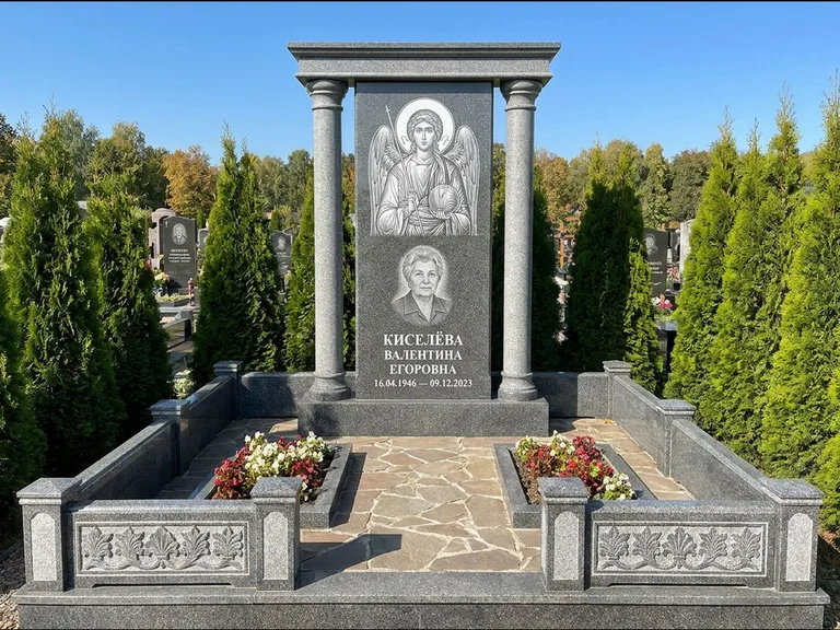 Памятник с гравировкой иконы: массивная стела с двускатным навершием-домиком — гравировка Николая Чудотворца, живая изгородь из туи, работа «Журавлёв» в Красноярске
