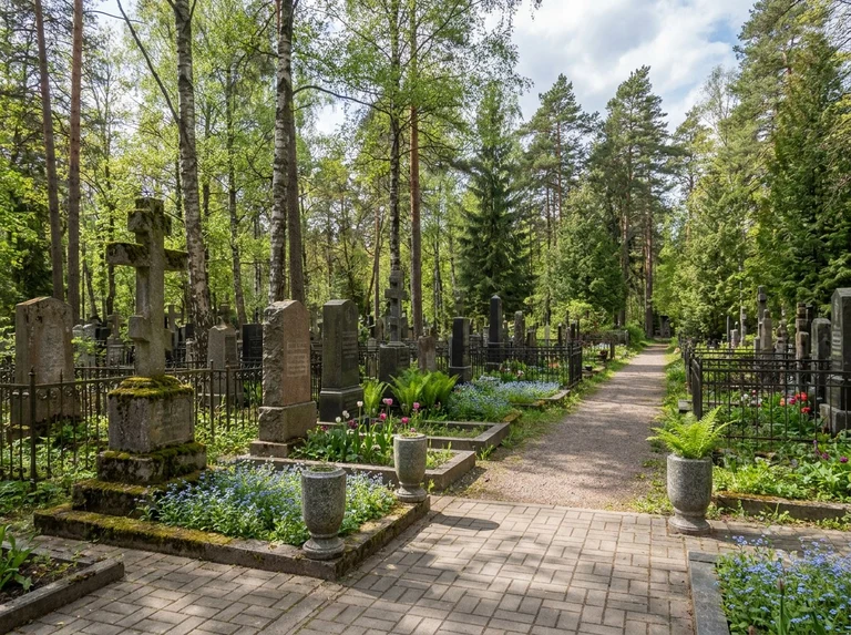 Гранитный памятник на ухоженном участке Шуваловского кладбища в Санкт-Петербурге среди деревьев