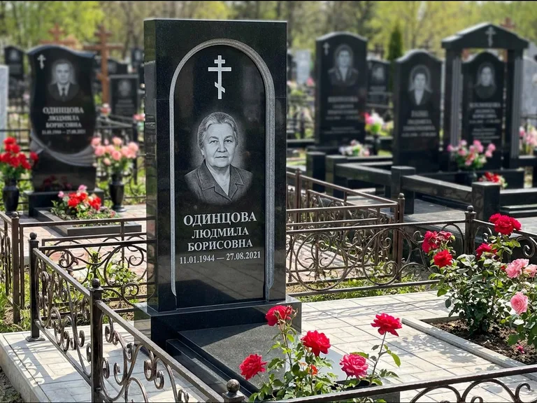 Памятник из чёрного гранита — скромная невысокая стела с крестом с терновым венцом, работа «Лаврентьева» в Красноярске