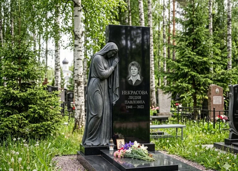 Гранитная фигура скорбящего мужчины у чёрной стелы в Красноярске